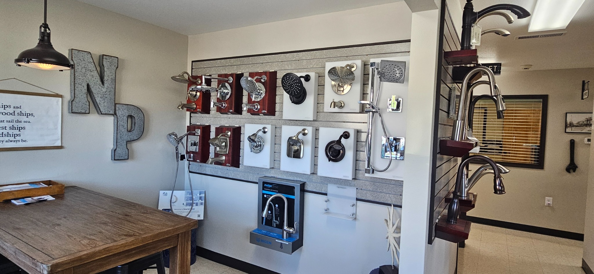 Wall-mounted showerhead and valve displays beside a rack of kitchen faucets