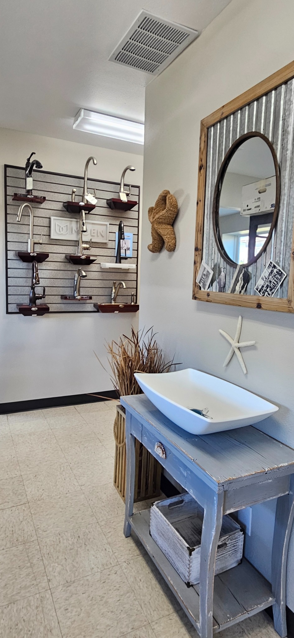 Tall view of a vessel basin, mirror, and nearby faucet display
